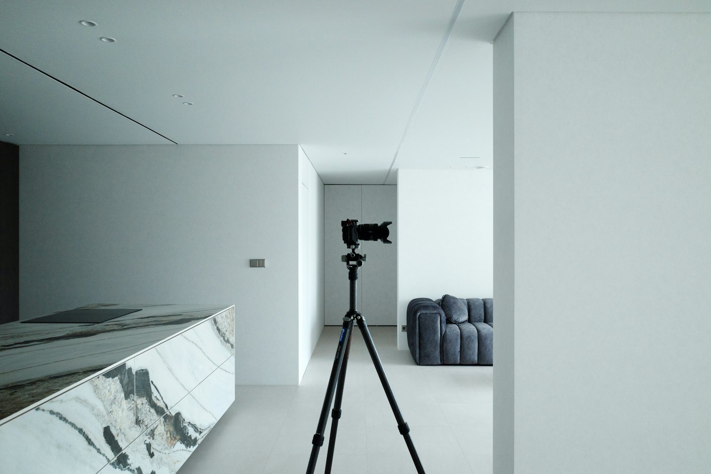 Fotocamera su treppiede che fotografa una moderna cucina e zona giorno.