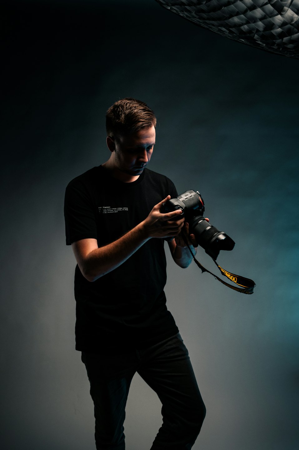 Un fotografo regola una macchina fotografica con un teleobiettivo in uno studio.